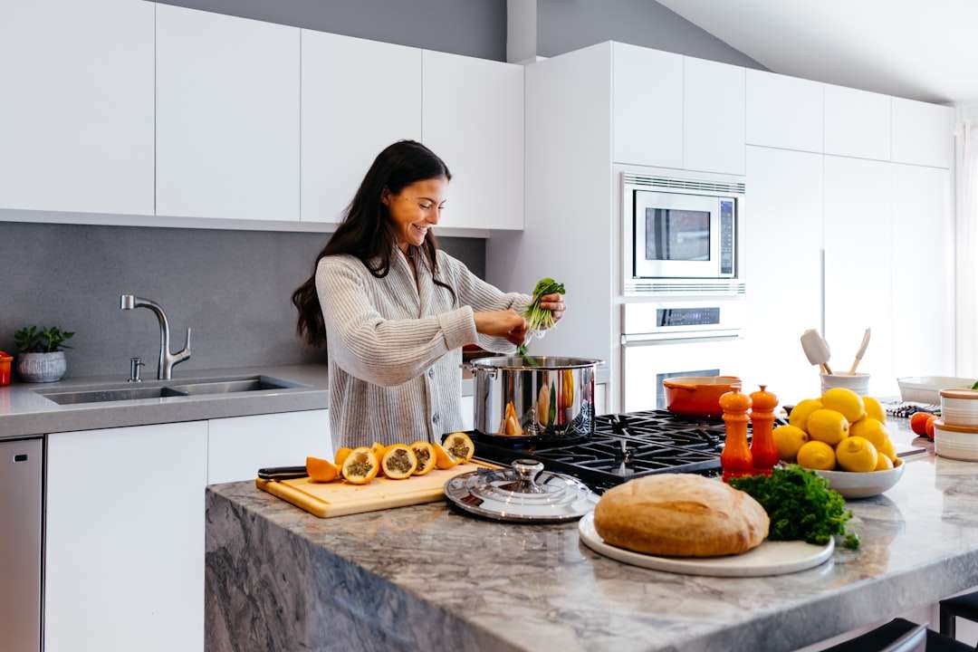 7-simple-tricks-to-improve-your-cooking-instantly A home cook standing in a bright modern kitchen preparing a meal at the counter
