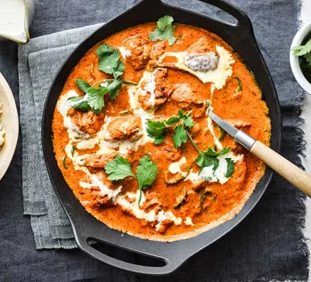 Rich and creamy Indian butter chicken simmering in a cast iron skillet
