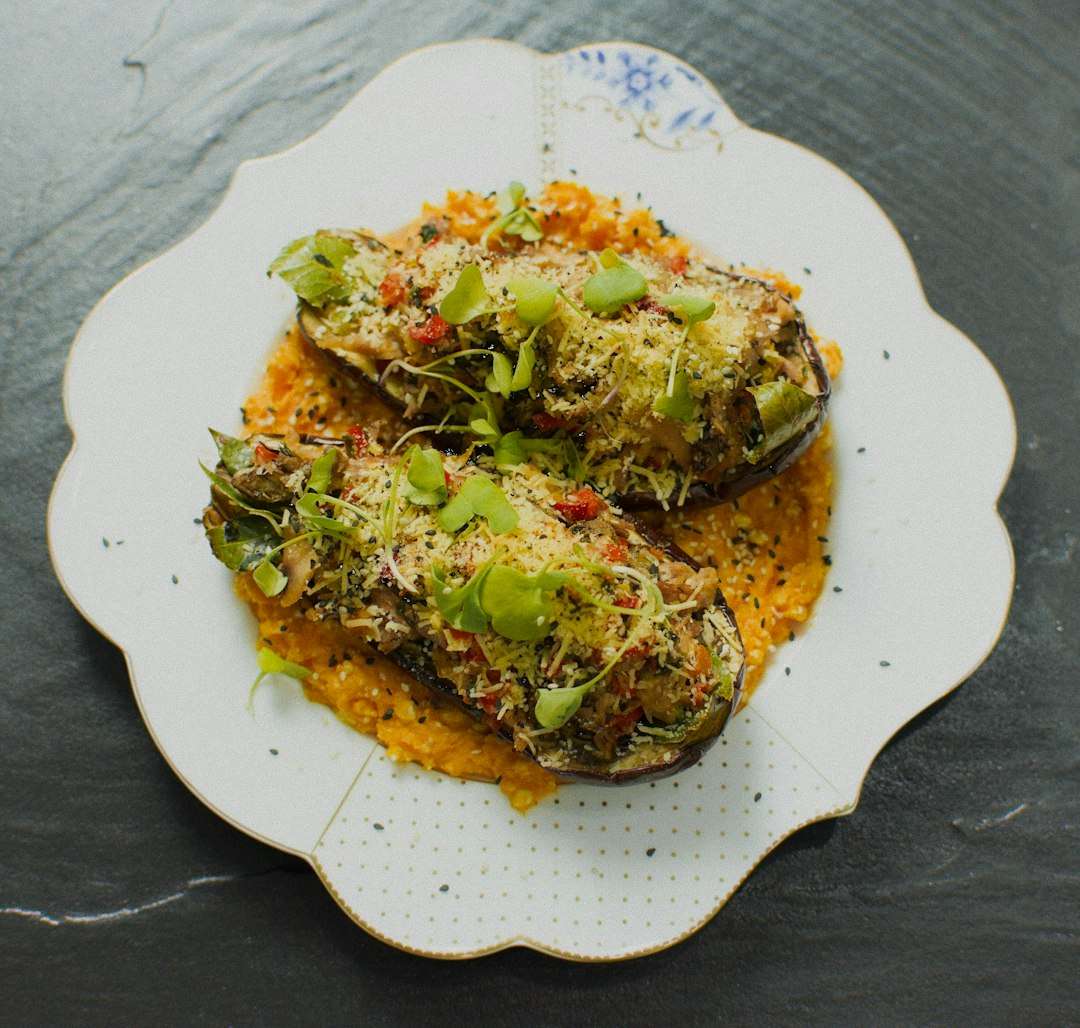 Baked stuffed bell zucchini served on a vintage white plate with savory sauce.