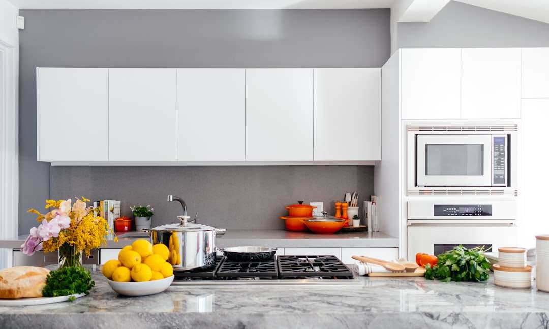 Modern bright white kitchen interior with a marble countertop and a pot on the stove.