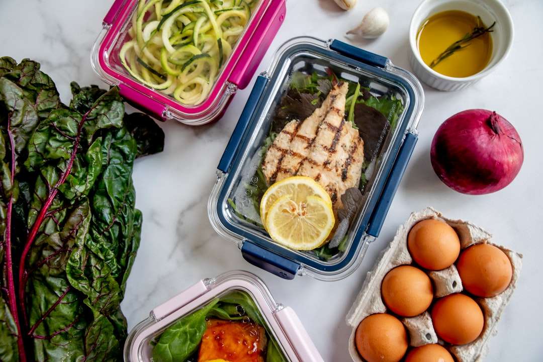 greek-chicken-meal-prep-bowls Meal prep containers with grilled chicken breast, zucchini noodles, and hard-boiled eggs.