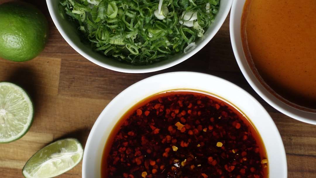 A bowl of spicy chili marinade next to a salad bowl of fresh green vegetables.