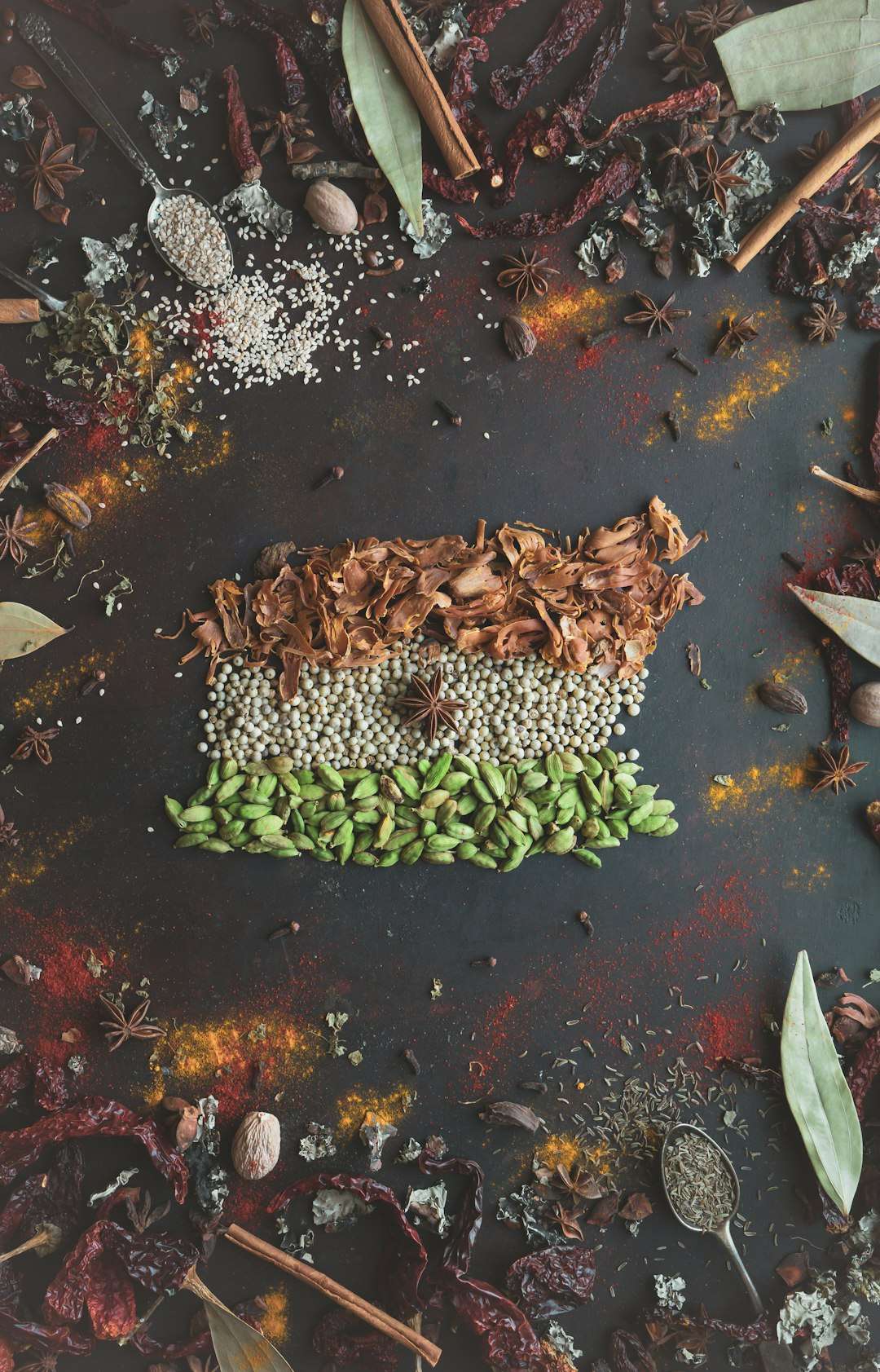 how-spices-changed-the-course-of-history A scattering of whole peppercorns and aromatic spices on a dark slate background