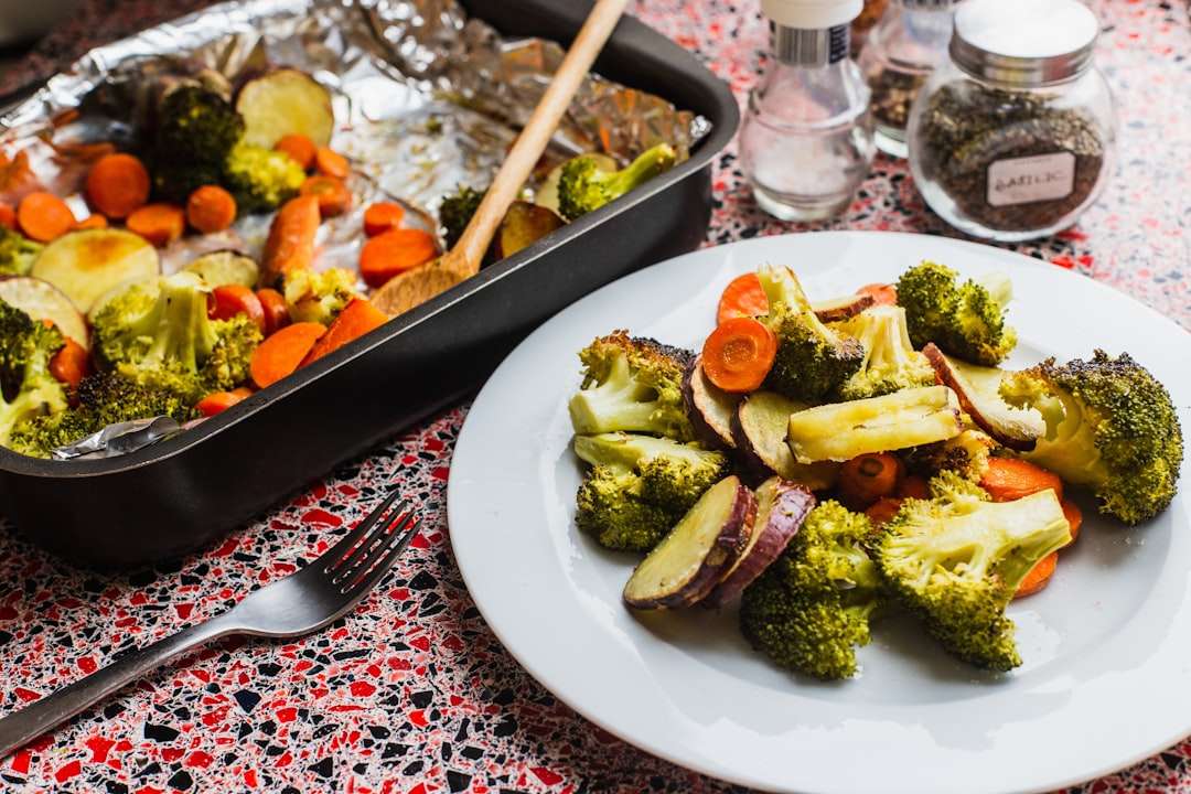 how-to-fix-overcooked-or-undercooked-meals A healthy dinner plate filled with roasted broccoli, potatoes, and carrots next to a baking pan.