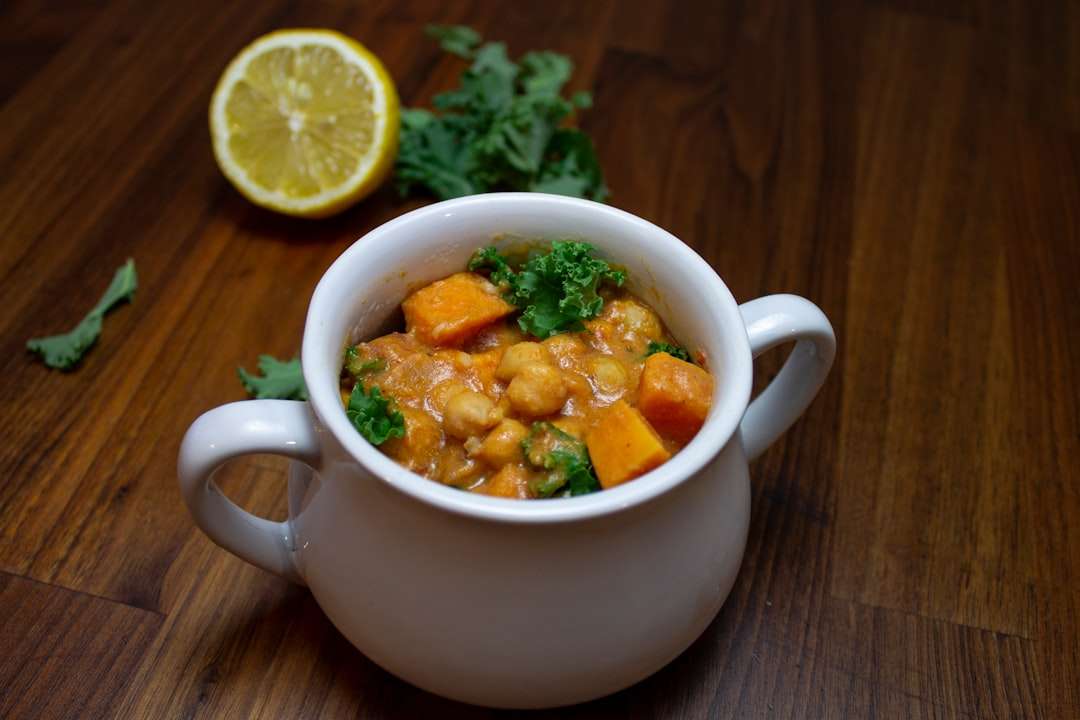 Warm bowl of Moroccan chickpea stew served with a fresh half lemon on the side