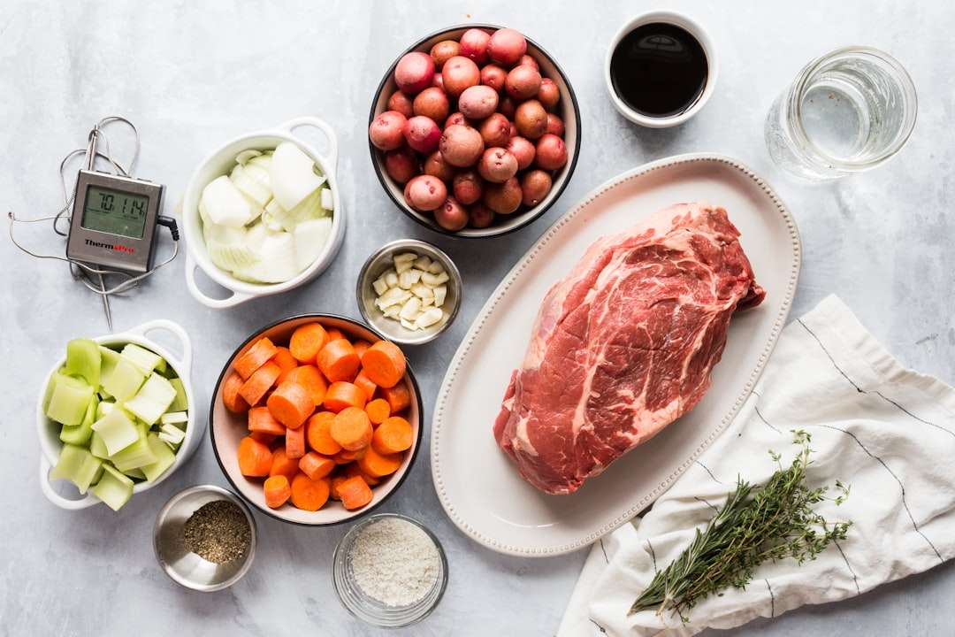 Raw ingredients for a pot roast including beef chuck, baby potatoes, and whole carrots