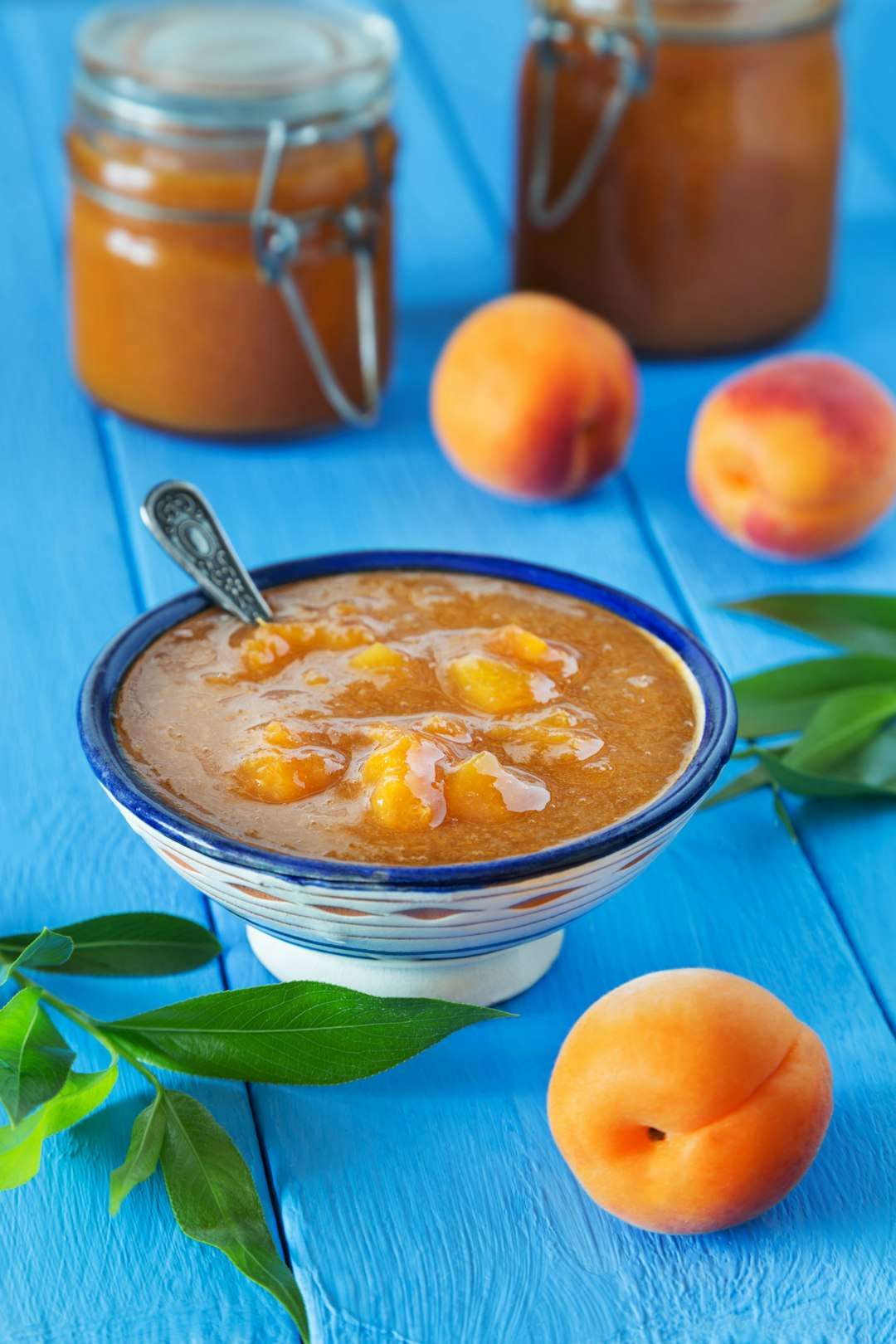 smoked-peach-bbq-sauce A bowl of chilled fresh peach soup or cream on a blue table with whole peaches