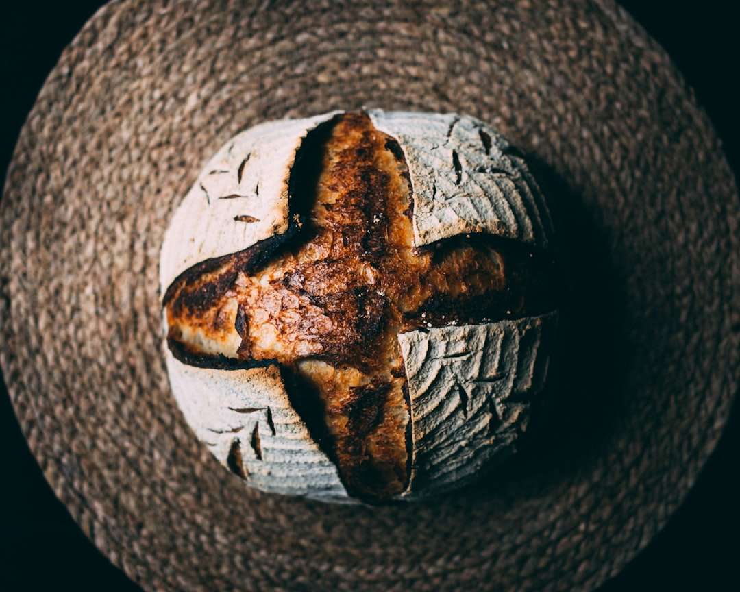 the-history-of-sourdough-bread-ancient-origins-and-evolution-1 A fresh loaf of sourdough artisan bread with a beautiful cross score mark on top.