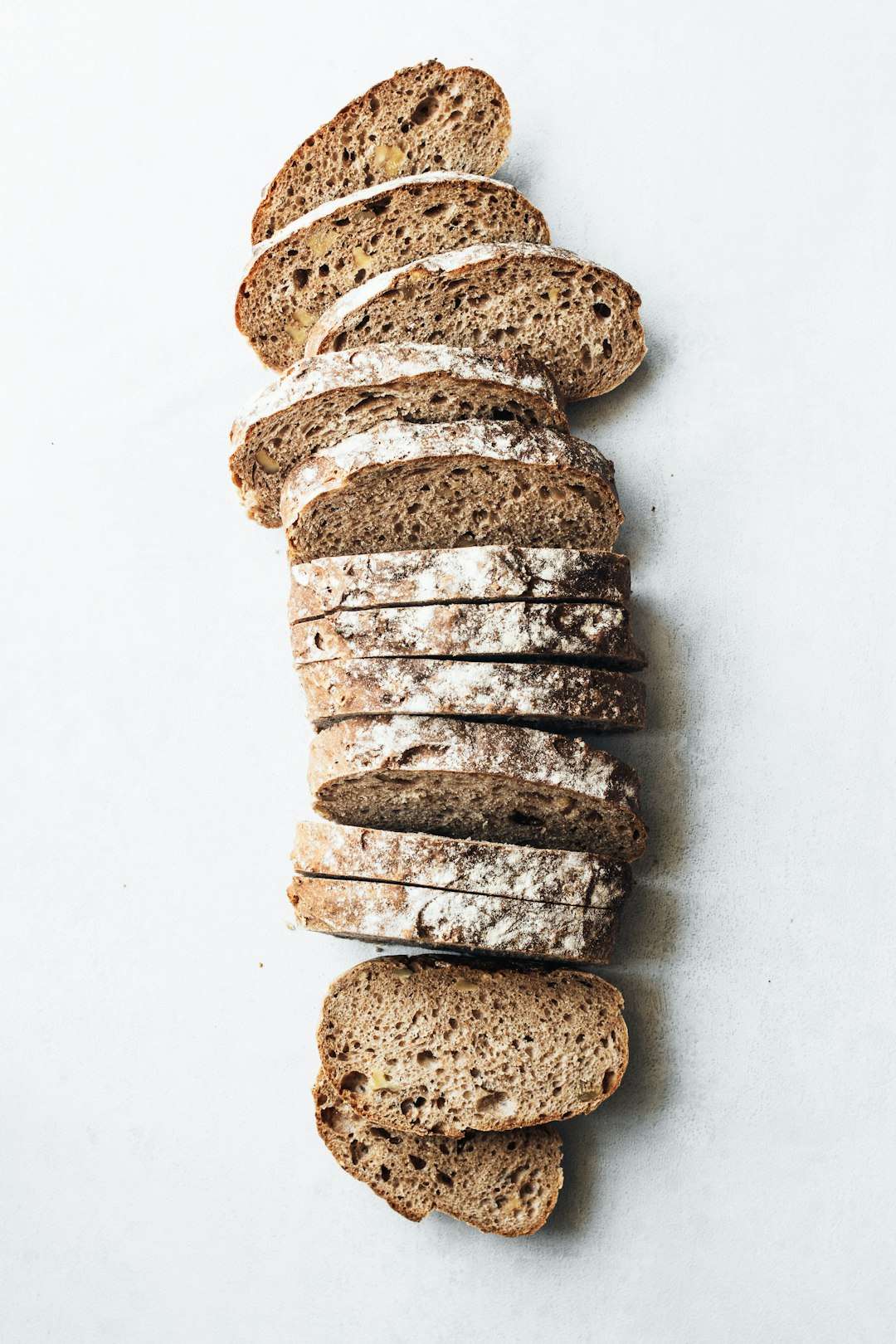 Slices of whole grain cereal bread stacked vertically on a white background.