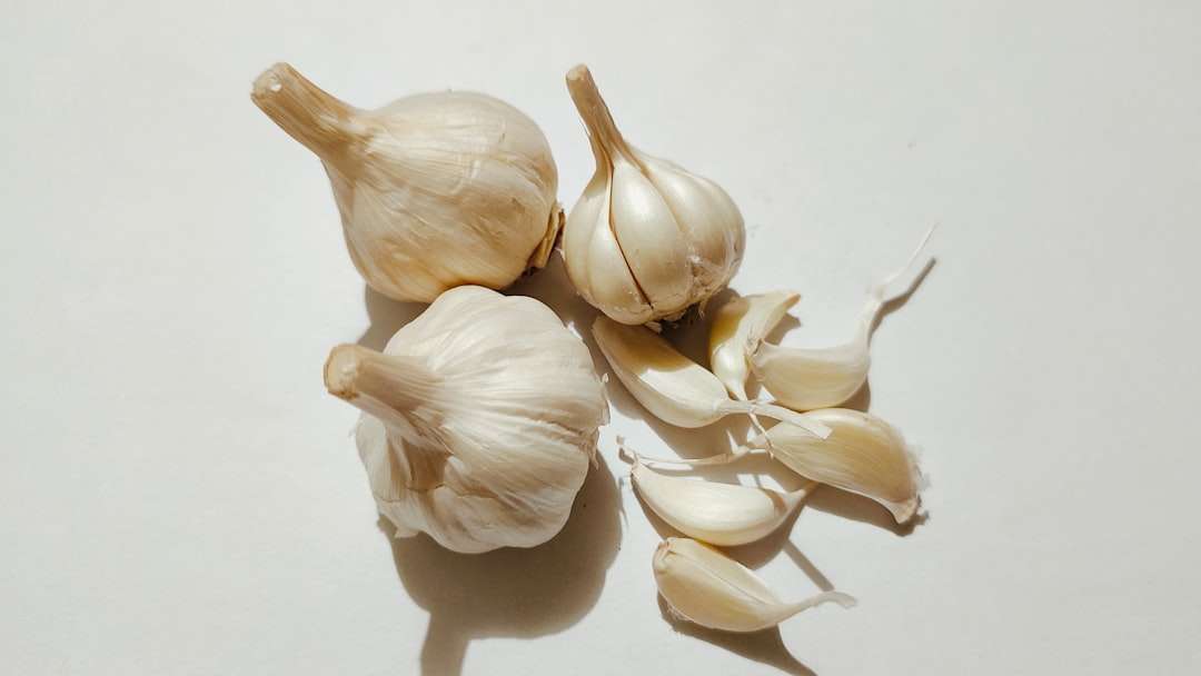 Whole garlic bulbs and peeled garlic cloves arranged on a clean white background.