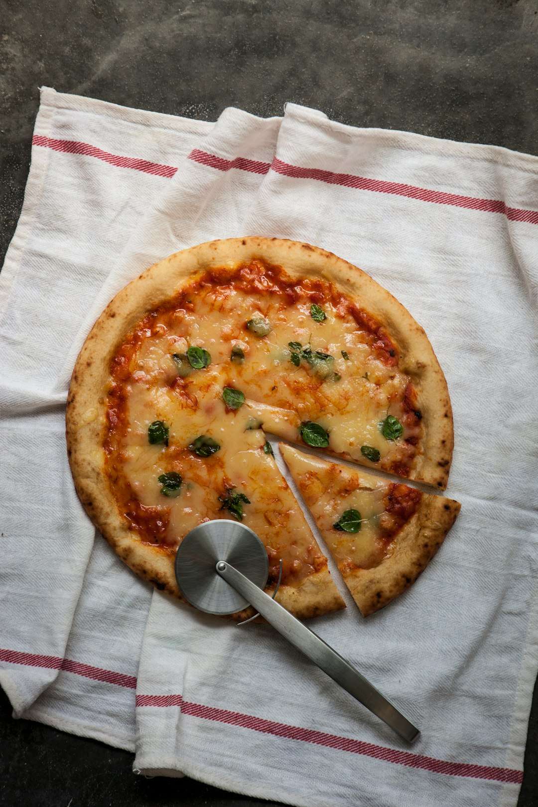 A whole homemade cheese and tomato pizza on a rustic wooden cutting board A whole homemade cheese and tomato pizza on a rustic wooden cutting board