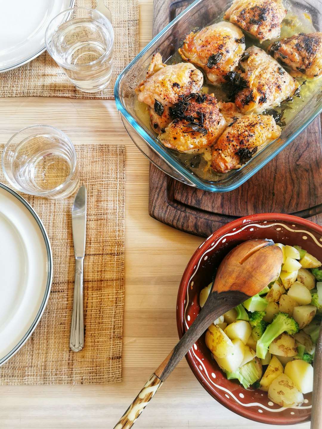 A glass baking dish filled with golden-brown baked chicken pieces on a rustic table