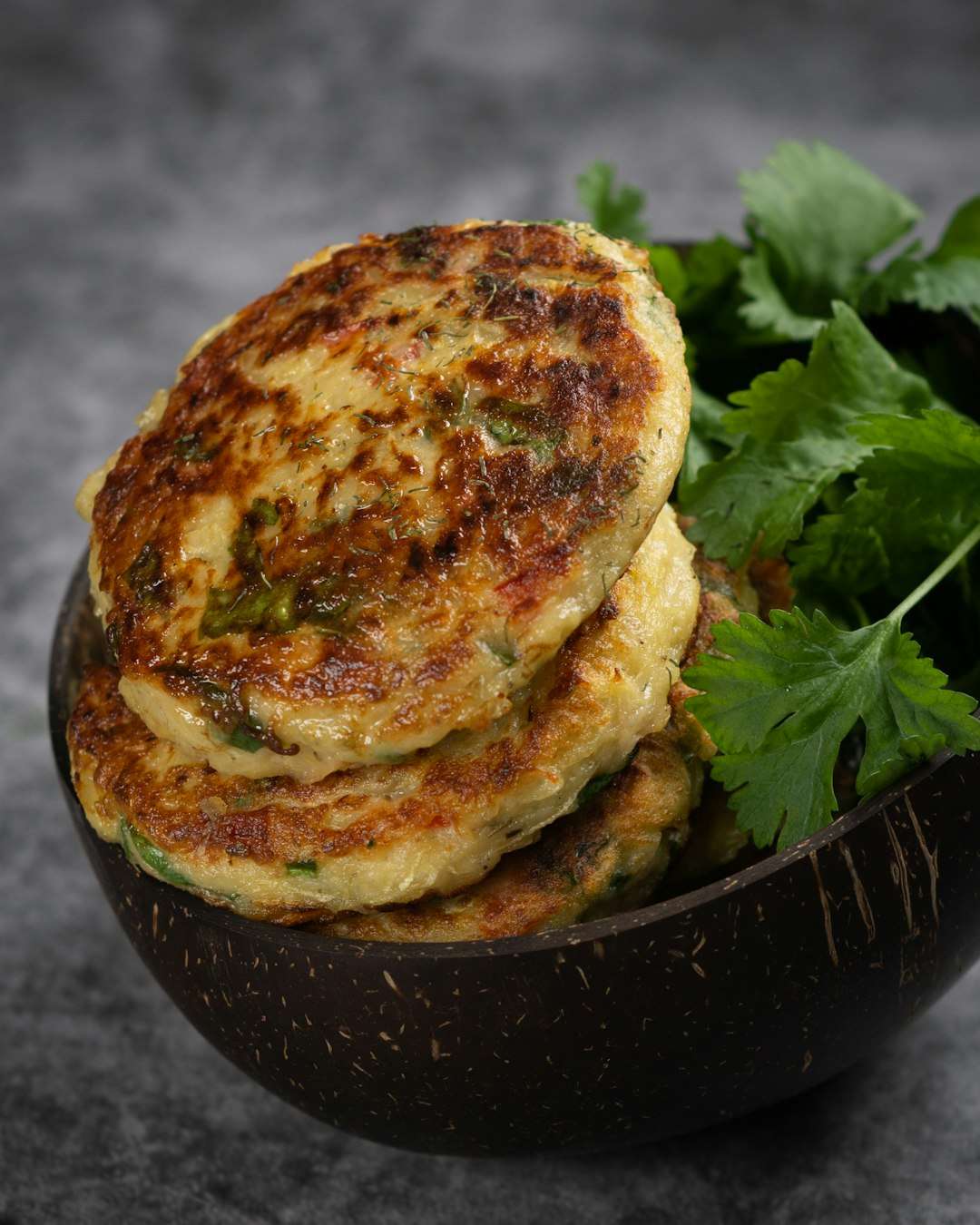 Stack of pan-fried zucchini fritters served with a side of sour cream and fresh dill