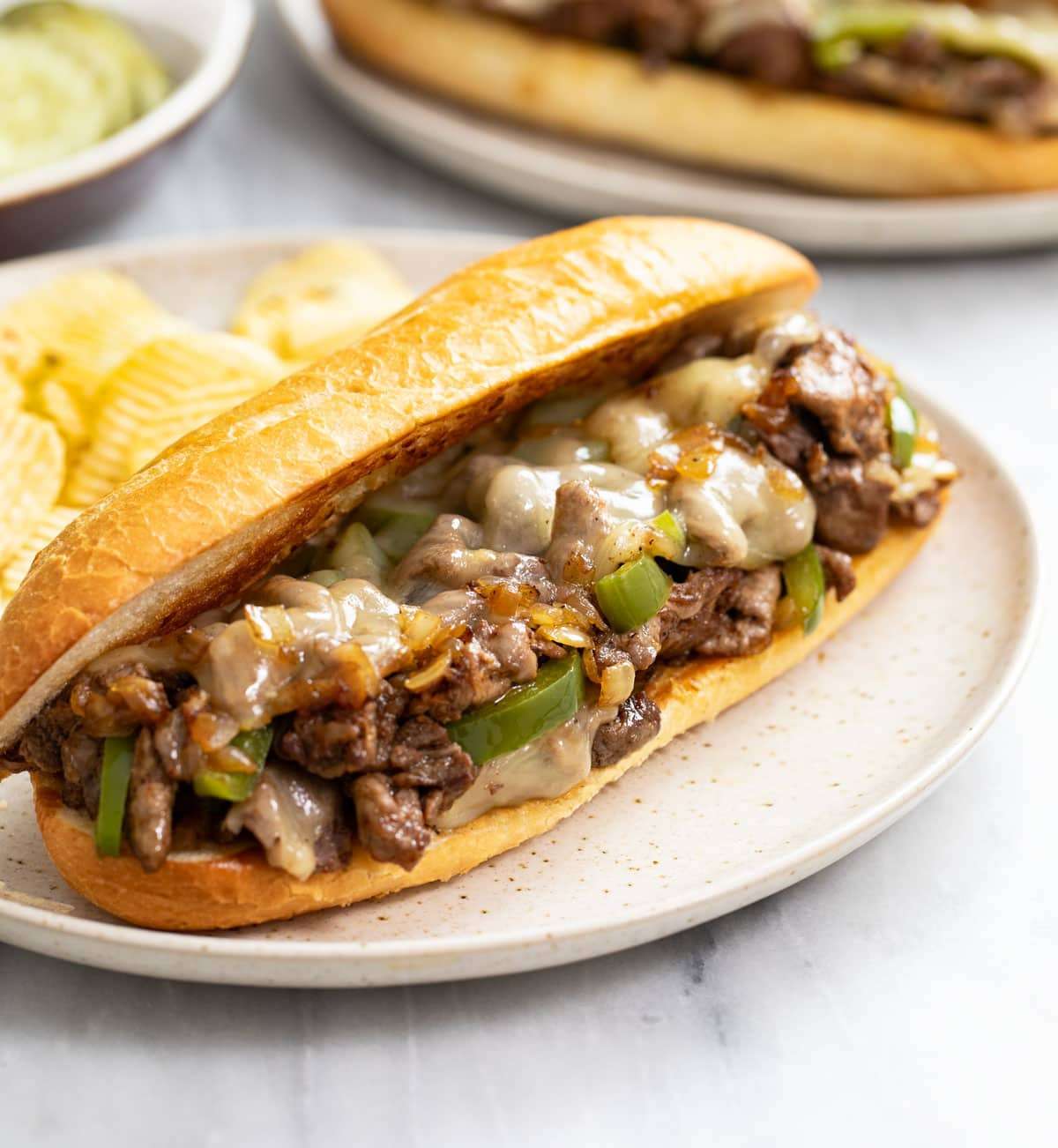 Classic Philly Cheesesteak Sandwich Best Match Day Meal A generous Philly cheesesteak sandwich loaded with shaved griddled beef and melted cheese on a plate