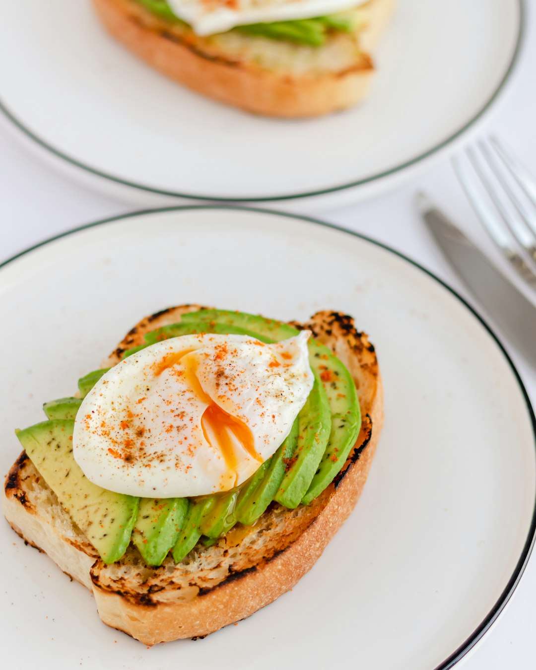 avocado-toast-poached-egg Gourmet avocado toast topped with a perfectly poached egg and fresh microgreens