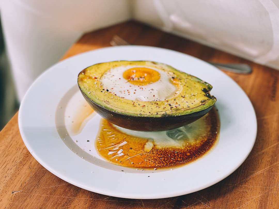 Healthy breakfast of baked eggs inside a halved avocado on a white plate