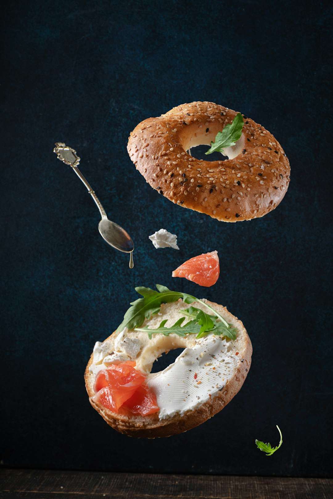 A classic toasted bagel layout next to fresh smoked salmon slices and capers on a dark background