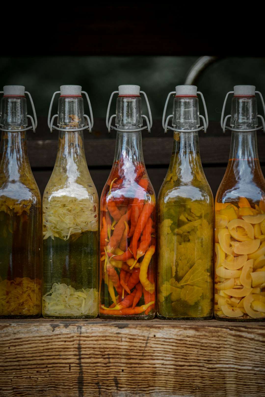 understanding-different-types-of-vinegar-in-cooking A row of clear glass swing-top bottles filled with different varieties of cooking oils